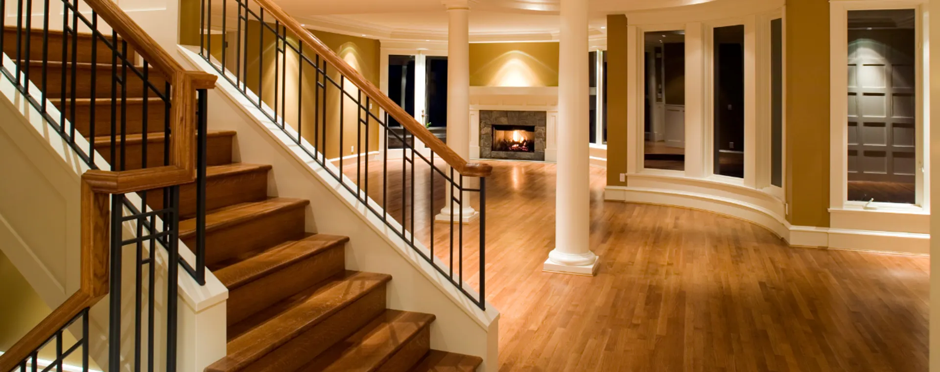 Wide-plank hardwood flooring flowing through a bright central North Carolina living room and staircase installed by APW